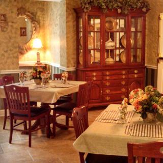 A warmly decorated dining room with a china cabinet and tables set for guests.