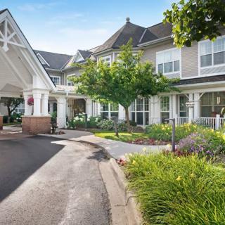 A well-landscaped building entrance with a driveway leading up to it.
