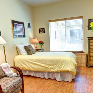 A cozy bedroom with a single bed, armchair, and window letting in natural light.