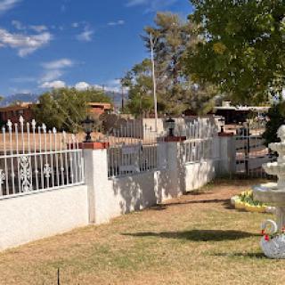 A serene outdoor scene featuring a white fence, well-maintained garden, and clear blue sky.