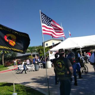 A gathering featuring an American flag and another flag, with attendees enjoying the outdoor event.