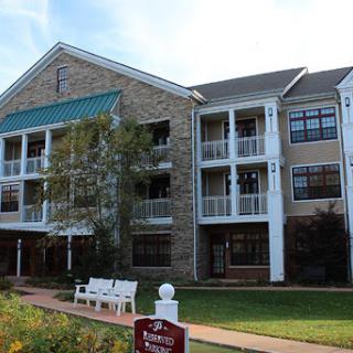 A residential building featuring stone architecture and balconies, set in a landscaped area.