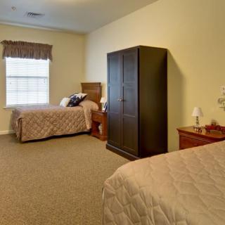 A cozy bedroom featuring two twin beds, a wardrobe, and bedside tables with a window providing natural light.