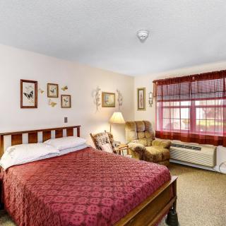 Cozy bedroom with a wooden bed, armchair, and decorative artwork.