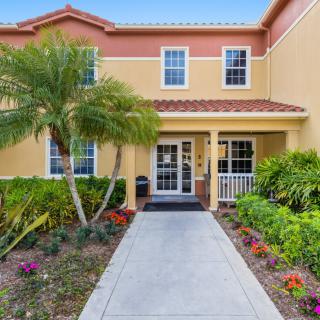 A welcoming house entrance with a neatly landscaped garden and a palm tree.