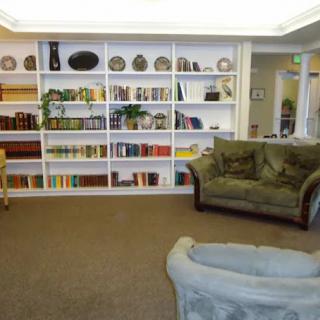 A cozy library space featuring bookshelves filled with books and decorative items, complemented by comfortable couches.