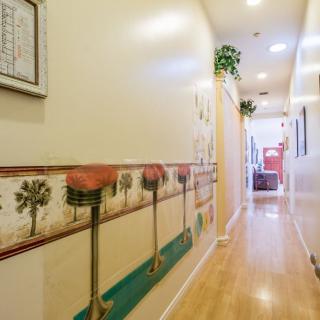 A well-lit hallway with wooden flooring and decorative wall art.