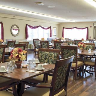 A neatly arranged dining area with tables and chairs, decorated with floral centerpieces.