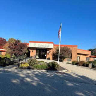 A bright day at the entrance of a community building with an American flag in front.
