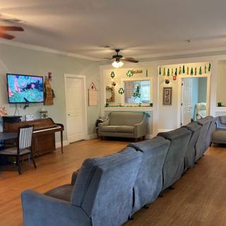 A spacious living room with a long sofa, piano, and a mounted television.