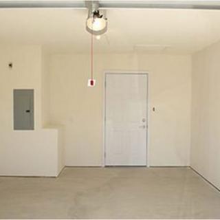 An empty garage with a closed door and ceiling light fixture.