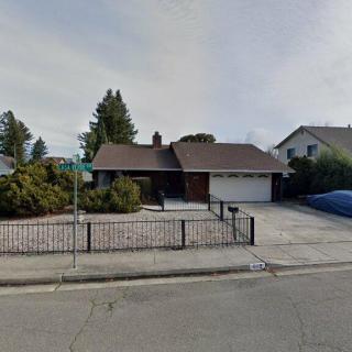 A suburban house with a fenced front yard and a driveway.