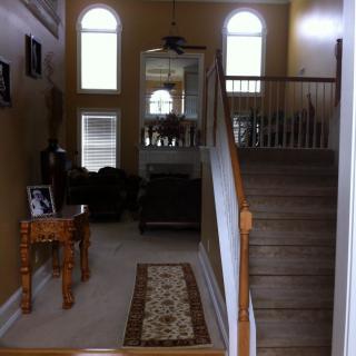 A well-lit interior view of a house with a staircase and living room area.
