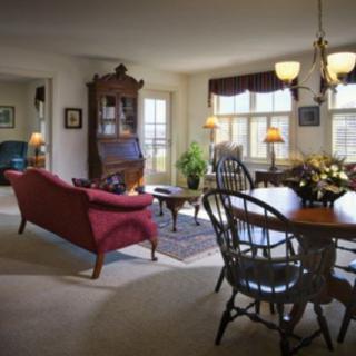 A traditional living room with a red sofa and a dining area featuring wooden furniture, warmly lit by a chandelier.