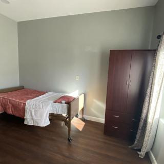 A minimalist bedroom with a single bed and wardrobe by the window.