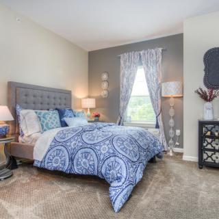 A cozy and well-decorated bedroom with a blue theme, featuring a comfortable bed, stylish curtains, and thoughtful lighting.