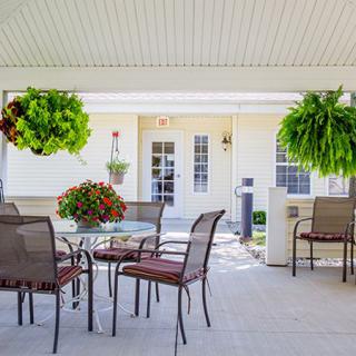 Cozy outdoor patio with seating and lush hanging plants.
