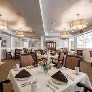 A formal dining room with neatly arranged tables and elegant lighting.