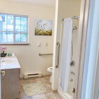 A bright and modern bathroom featuring a shower, sink, and window with floral decor.