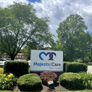 A sign for Majestic Care surrounded by lush greenery and trees.