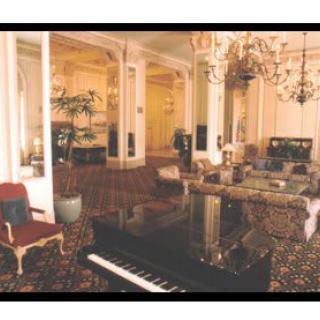 A luxurious room with classic decor featuring a grand piano and ornate chandeliers.