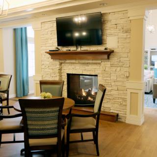 A cozy living room with a stone fireplace, mounted television, and a dining table with chairs.