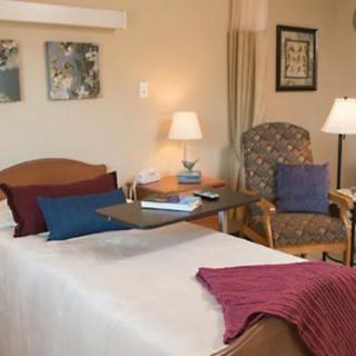 Comfortable hospital room with a bed, chair, and lamps.