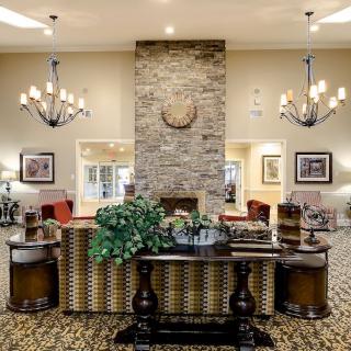 A cozy and elegant lobby featuring chandeliers, a brick fireplace, and a comfortable seating area.