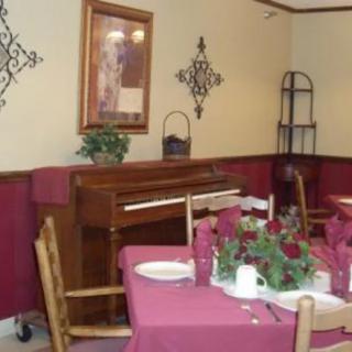 A cozy dining room with a piano and a beautifully set table.