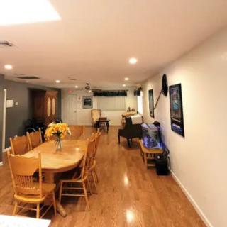 A spacious dining area with a wooden floor, featuring a table with chairs and wall decorations.