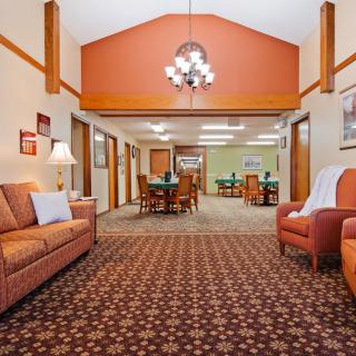 Comfortable lounge area with sofas and armchairs, featuring warm lighting and patterned carpet.