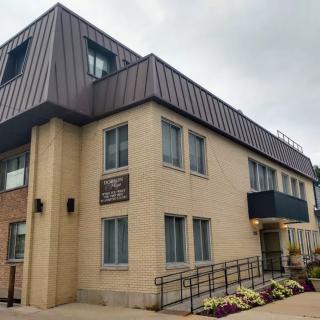 A two-story office building with a brick facade and a sloped roof on an overcast day.