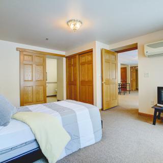 A cozy bedroom with a neatly made bed, wooden wardrobes, and soft lighting.