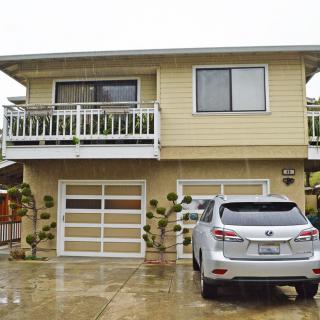 A two-story residential house with a garage and car parked in the driveway on an overcast day.