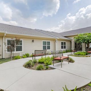 A serene courtyard with benches surrounded by well-maintained landscaping and a pathway.