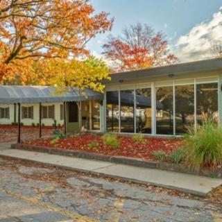 A modern building surrounded by autumn foliage under a cloudy sky.