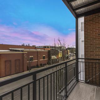 A view from a balcony overlooking the city at sunset, showcasing urban architecture and vibrant skies.