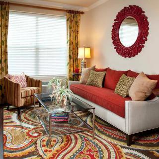 A cozy living room with a colorful rug, red sofa, and patterned decor.