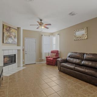 A cozy living room featuring a leather sofa and an armchair, with a fireplace and ceiling fan providing warmth and comfort.