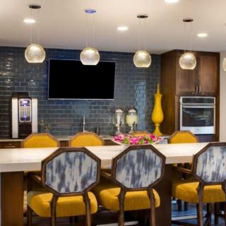 A modern kitchen with vibrant yellow seating and sleek pendant lighting.