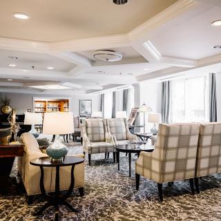 A spacious living room with plaid chairs and elegant decor, featuring ample natural light.