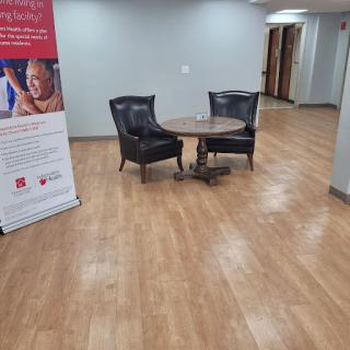 A cozy waiting area featuring two black chairs and a table, complemented by a promotional banner.