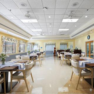 A spacious and well-lit dining hall with neatly arranged tables and chairs.