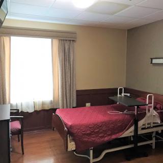 A view of a patient room in a hospital, featuring a bed, window, and medical amenities.