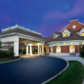 A well-lit hotel exterior with a driveway at night.