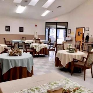 A well-arranged dining area with multiple tables covered in tablecloths, bright lighting, and a welcoming atmosphere.
