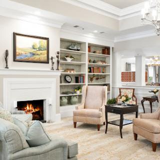A cozy and elegantly designed living room featuring a fireplace, bookshelves filled with decor, and comfortable seating.