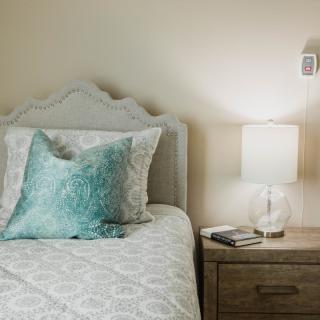 A cozy bedroom with a decorative pillow and a nightstand lamp.