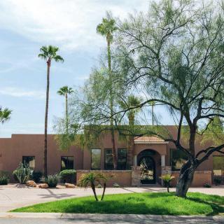 A residential building surrounded by desert landscaping and palm trees on a sunny day.