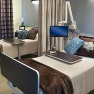 A modern hospital room equipped with medical devices and comfortable furnishings.